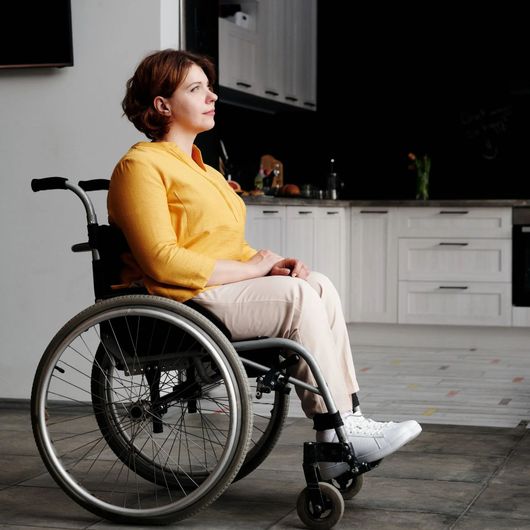 Woman in yellow shirt in a wheelchair in a home