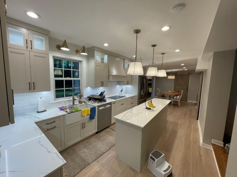 A kitchen with white cabinets , white counter tops , stainless steel appliances and a large island.