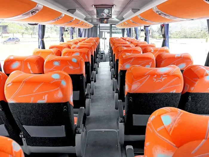 O interior de um ônibus com assentos laranja e pretos
