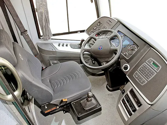 O interior de um ônibus com volante e assentos