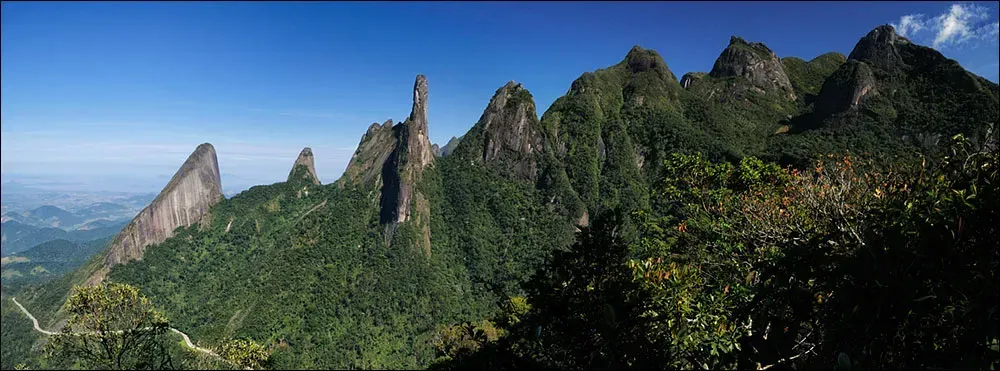 Uma montanha coberta de árvores e pedras com um céu azul ao fundo