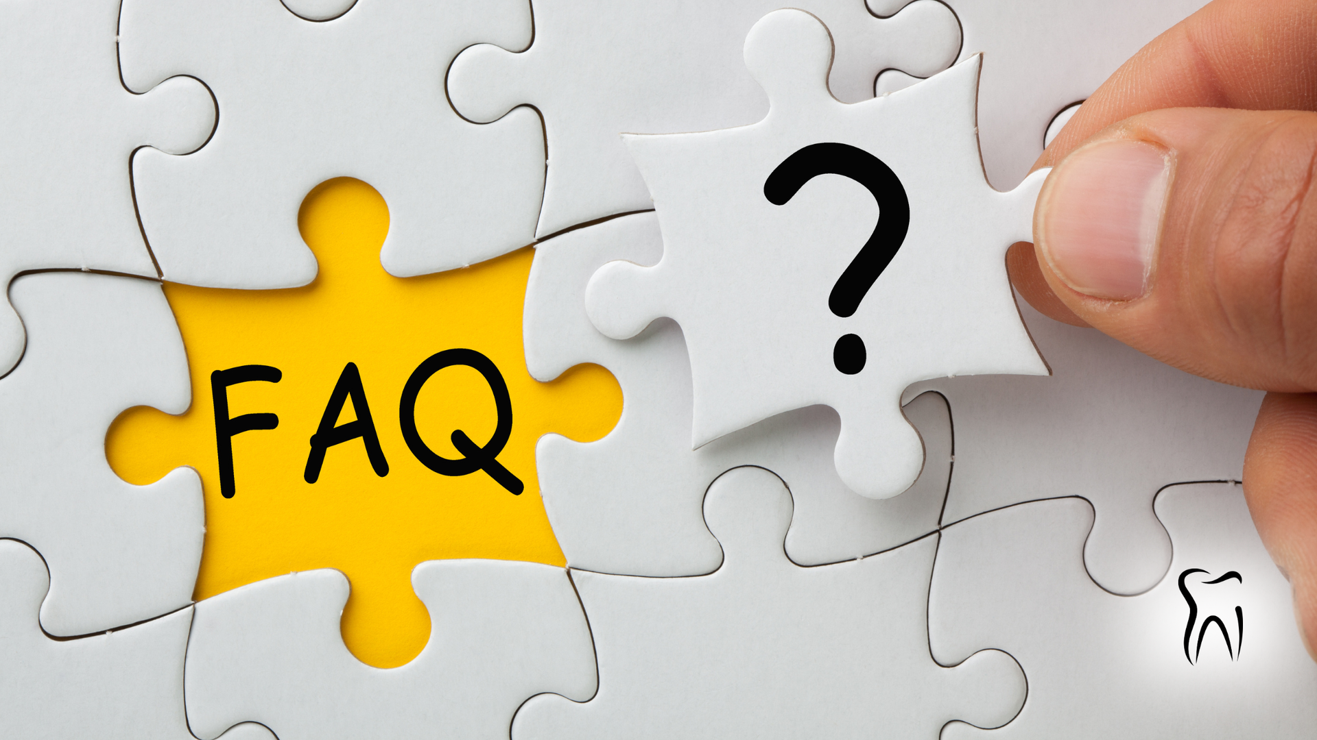 Hand placing question mark puzzle piece into a FAQ jigsaw puzzle.