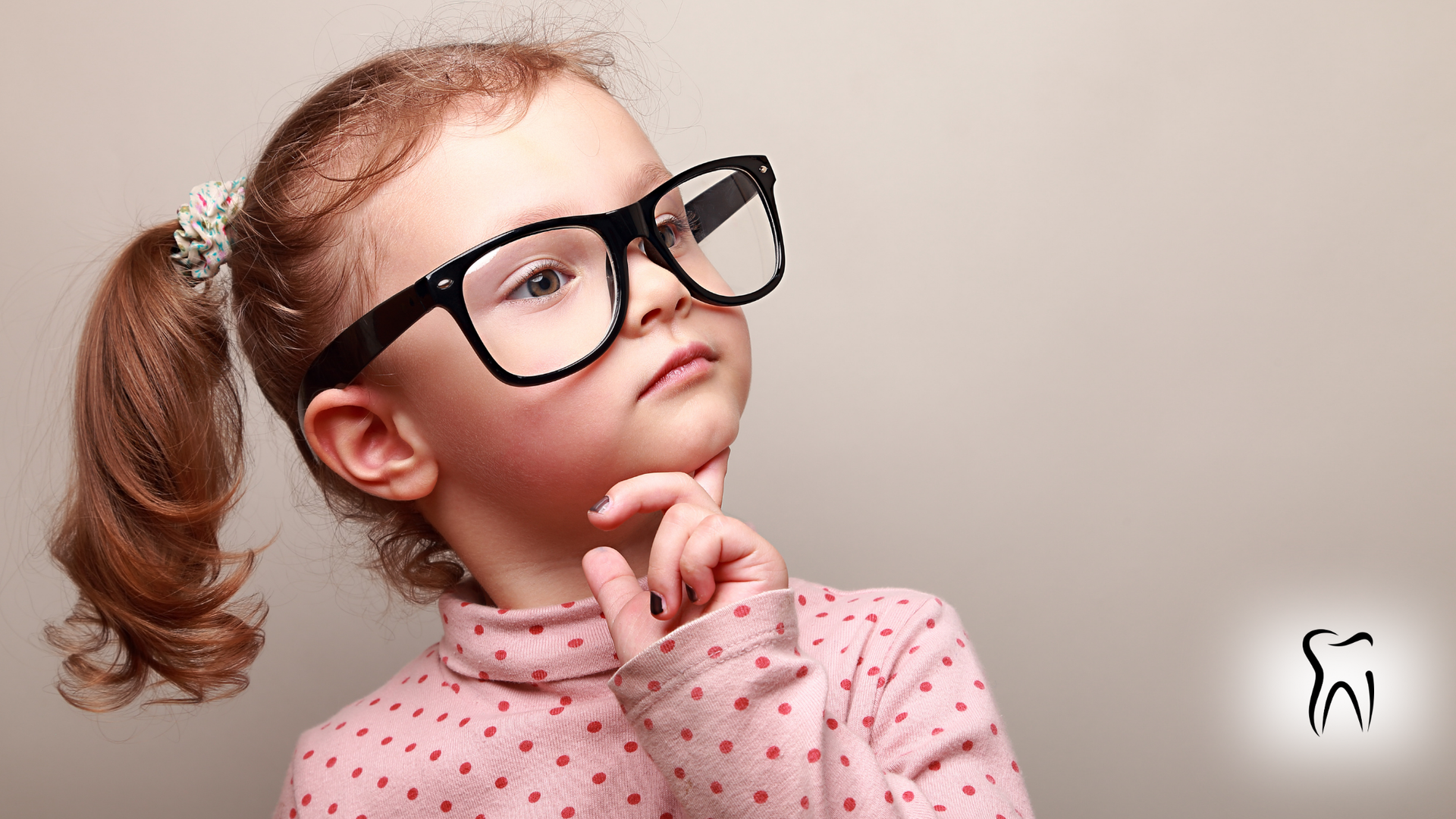 Young child with glasses, pink shirt, and ponytail, thoughtfully touching chin, near a dental icon.