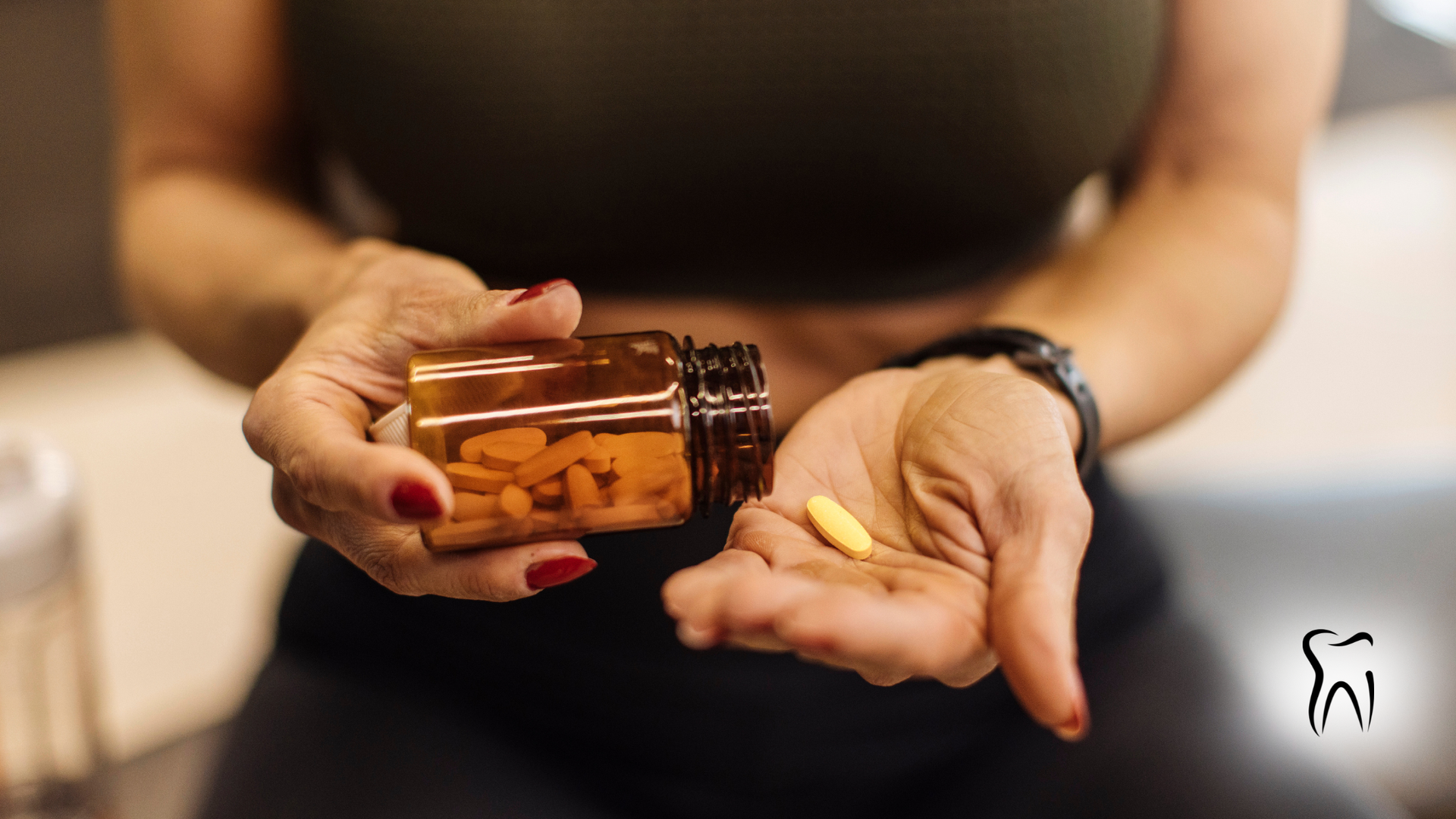 Person holding a bottle of pills, pouring one into their palm. The person wears a sports bra and watch.