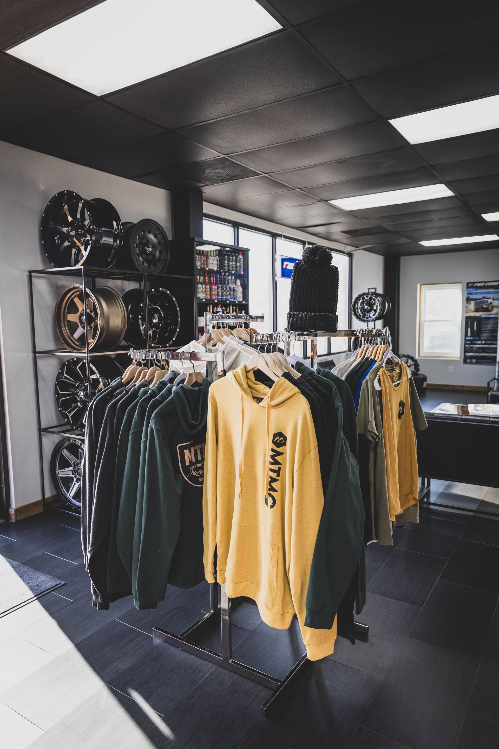 Apparel and car wheels displayed in a shop with bright lighting and dark floors. | Mountain Top Service Center