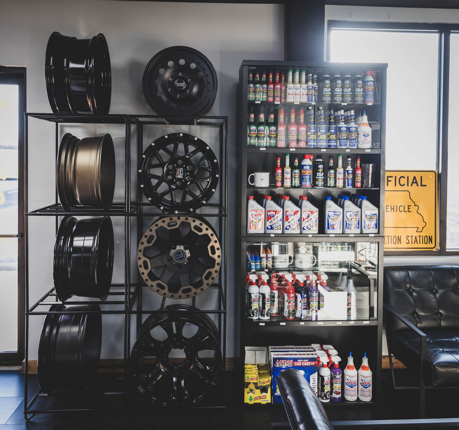 Tires and rims on display in an auto shop next to a cabinet with fluids and a couch. | Mountain Top Service Center