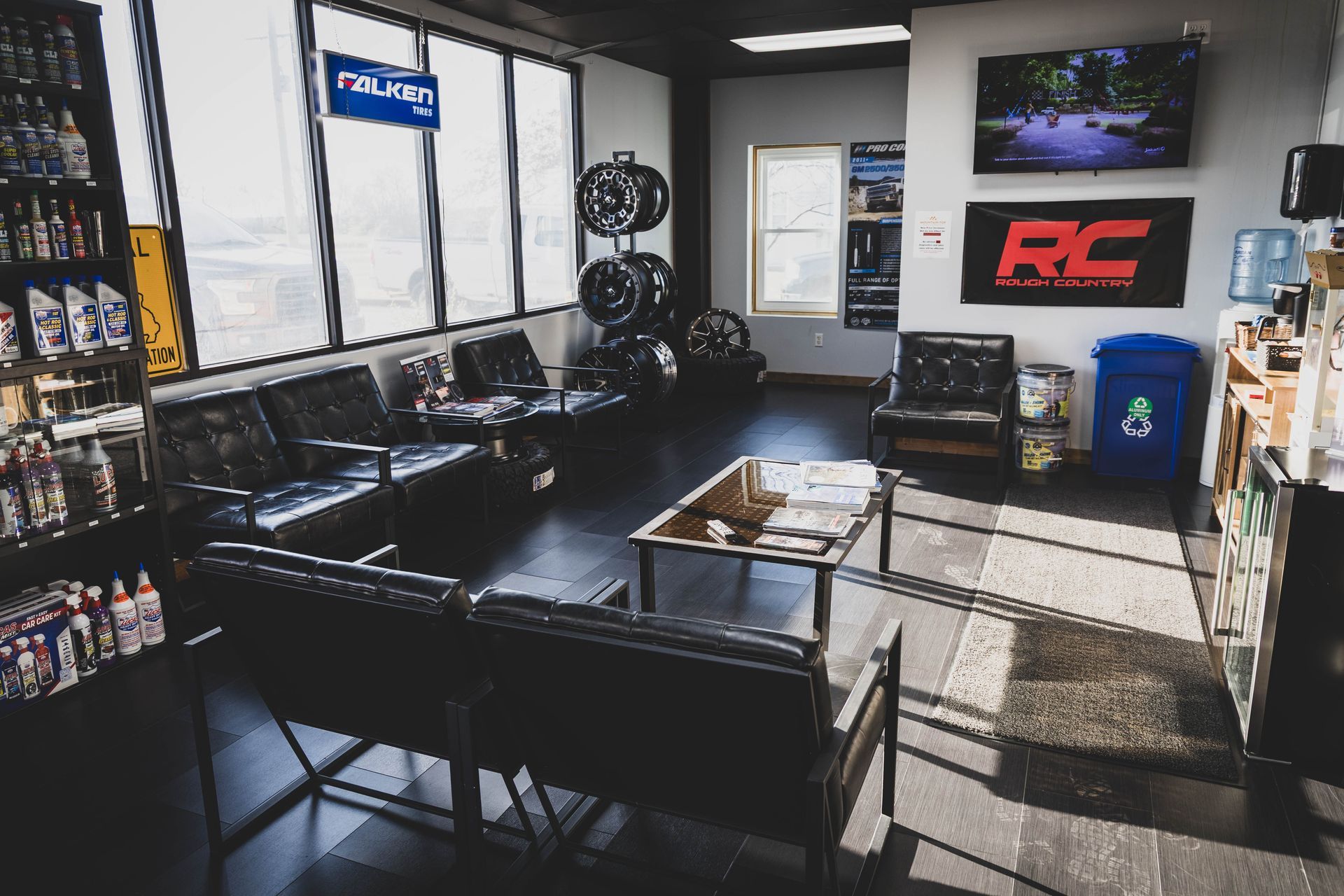 Waiting room in auto shop with black couches, tires, and a small coffee table. | Mountain Top Service Center