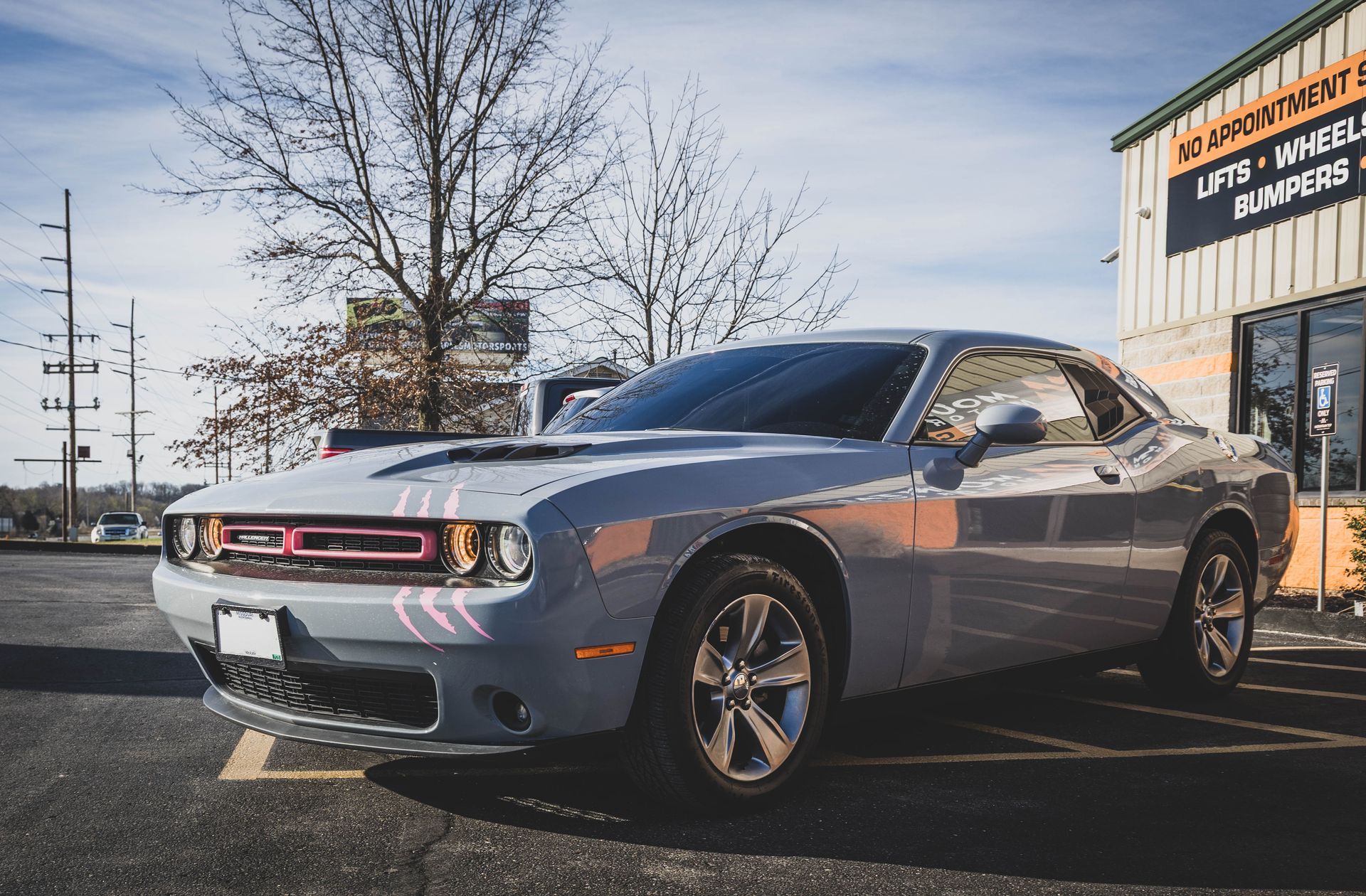 Grey Dodge Challenger parked in front of a building with tire and wheel signs. | Mountain Top Service Center