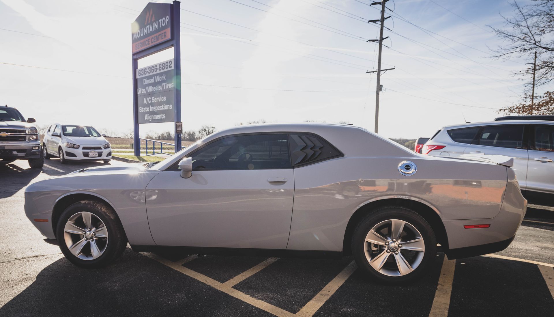 Gray Dodge Challenger parked in a lot with other vehicles and a business sign in the background. | Mountain Top Service Center