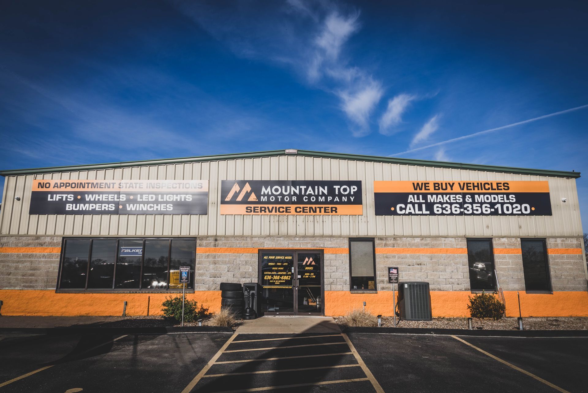 Mountain Top Motors building, exterior view. Gray and orange, blue sky. Text: buy/sell vehicles, service center. | Mountain Top Service Center