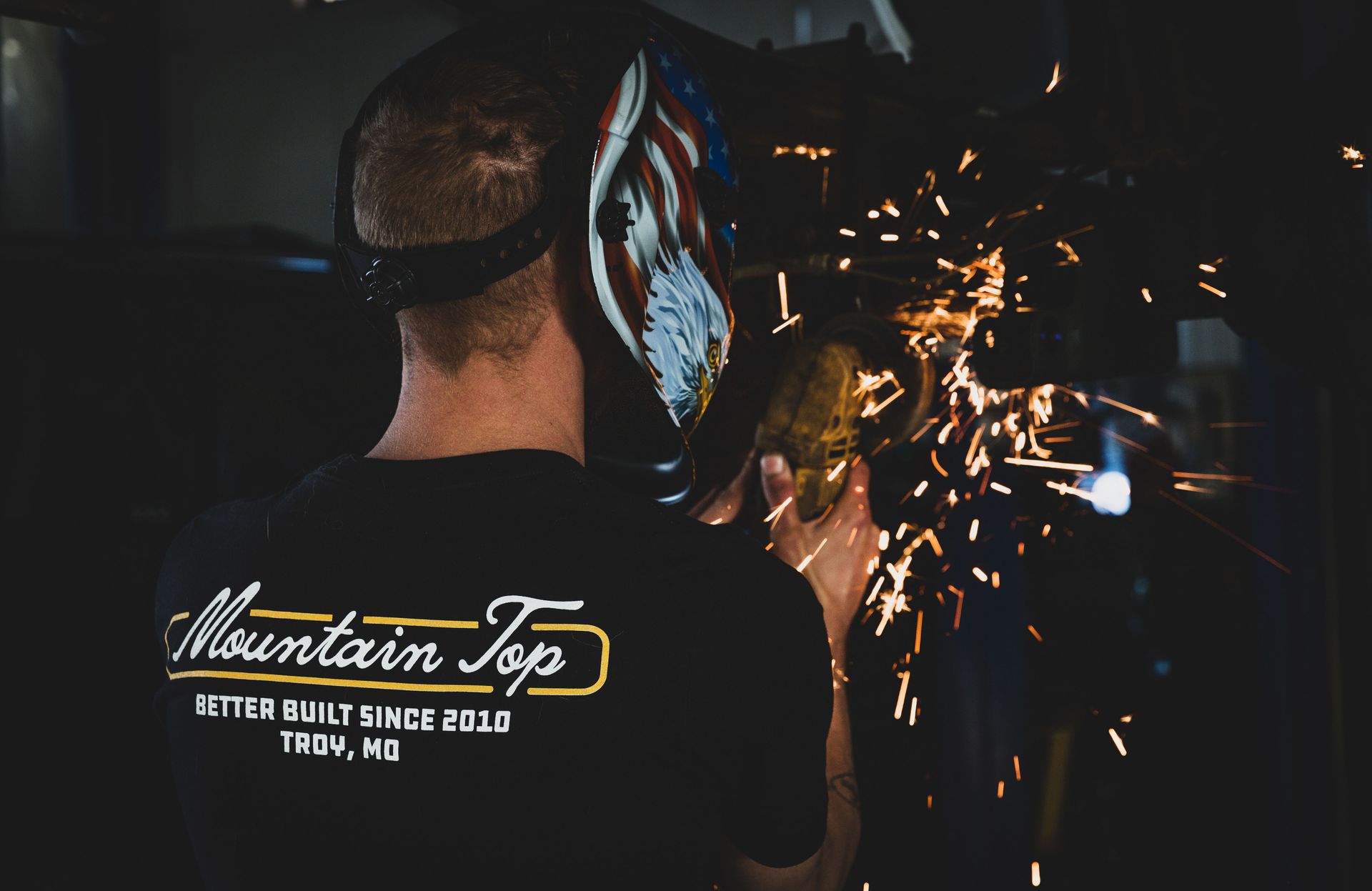 Welder in a workshop, sparks flying. Wearing a Mountain Top shirt. | Mountain Top Service Center