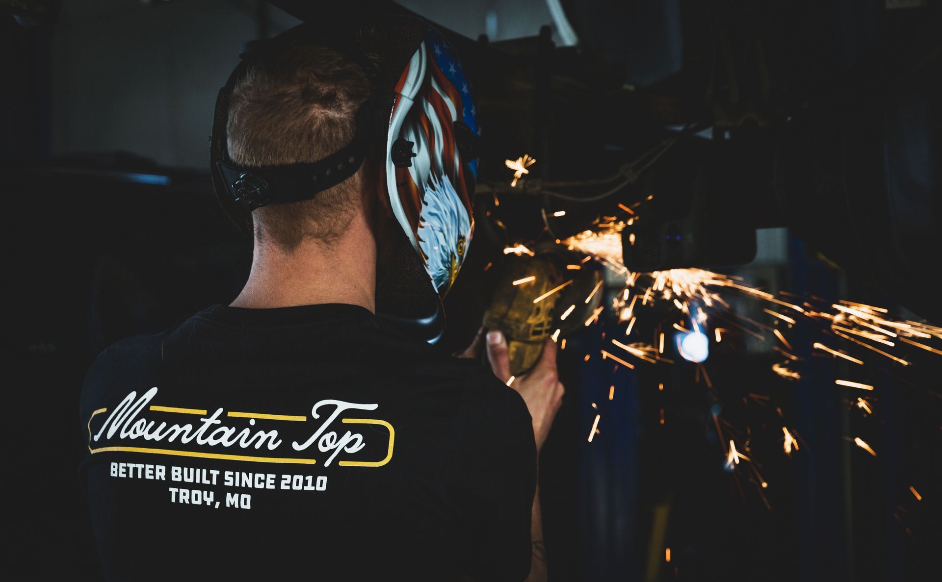 Welder wearing a mask working in a shop, sparks flying, 