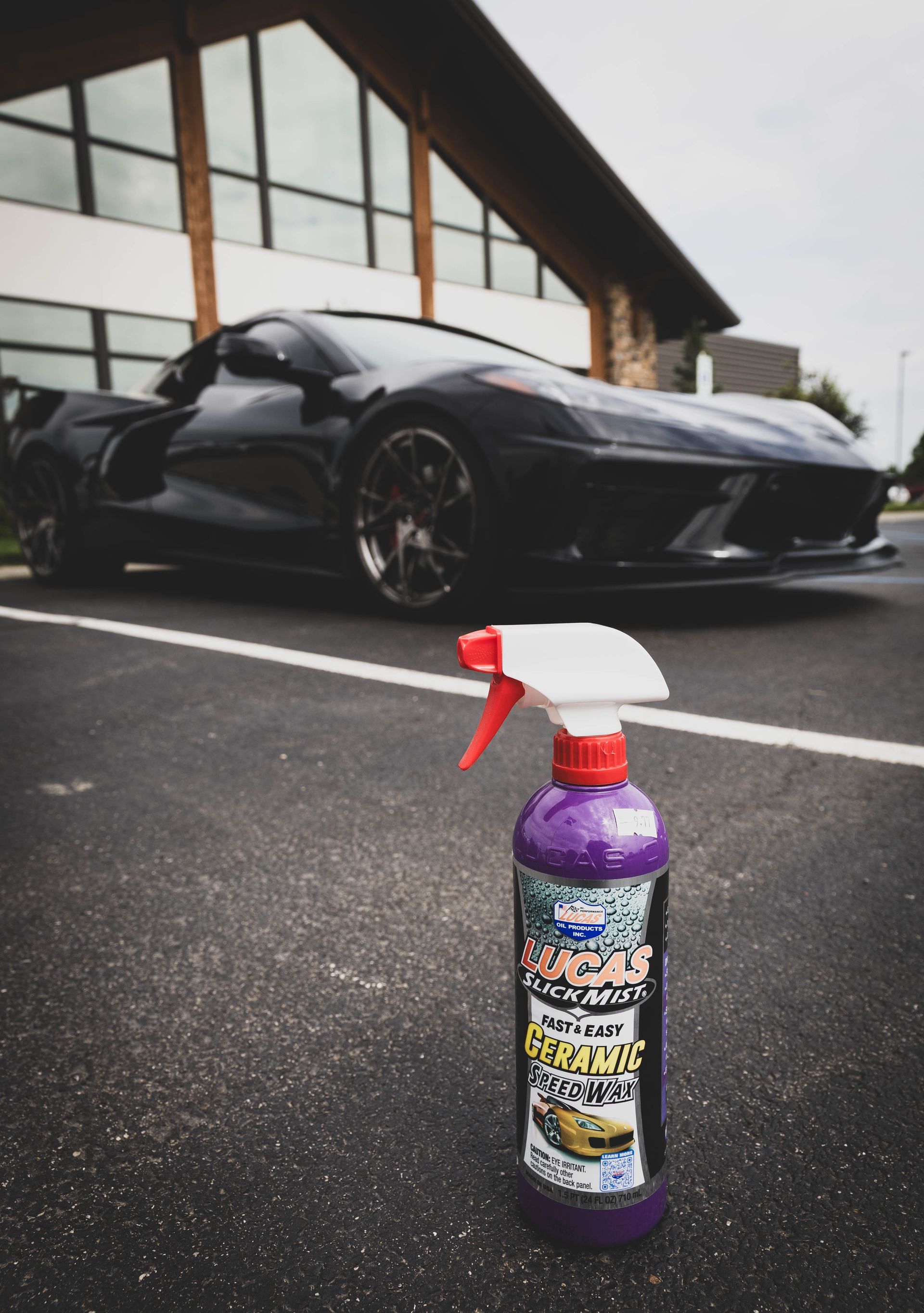 A car detailing spray bottle in front of a shiny black sports car parked on asphalt. | Mountain Top Service Center