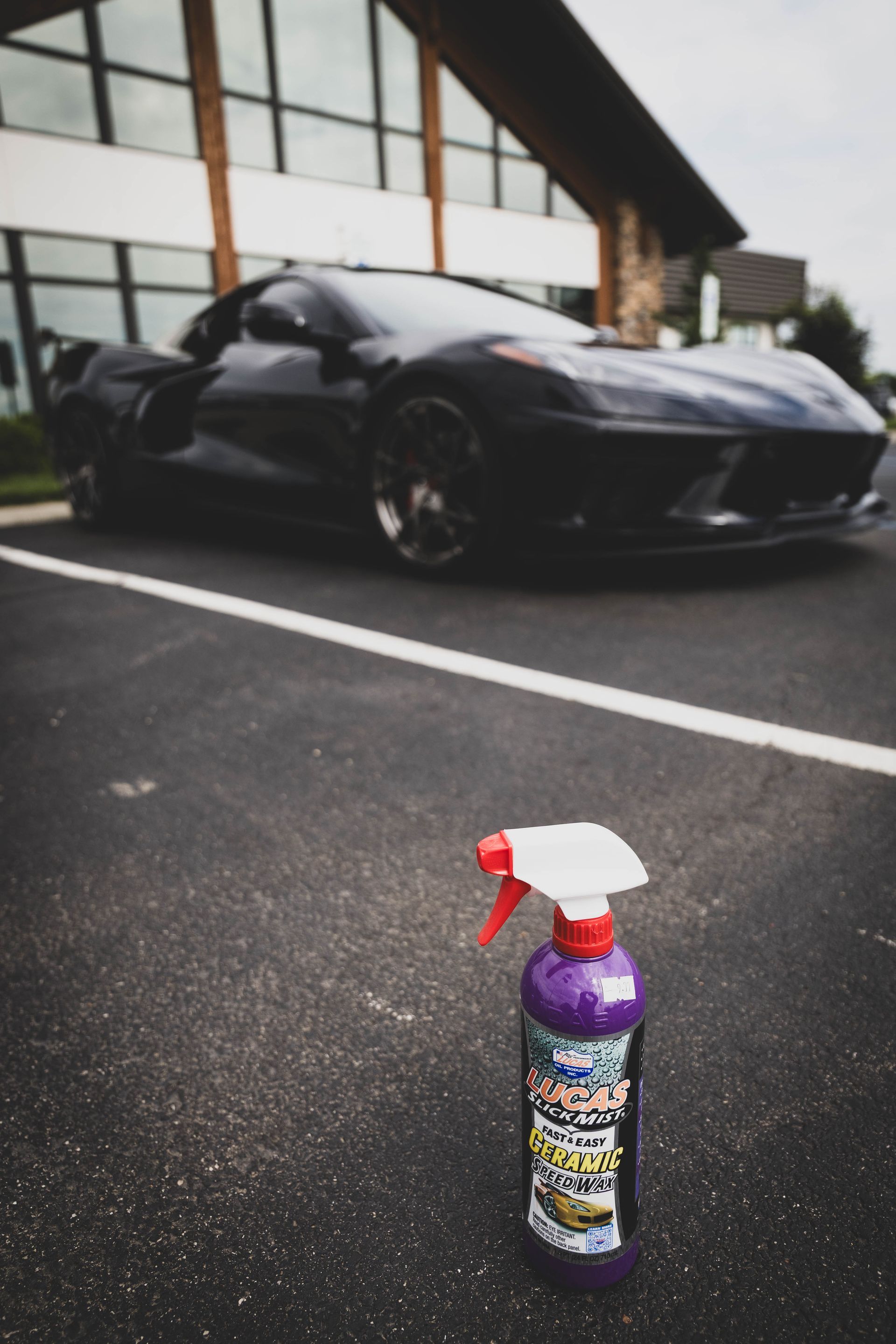 Purple car detailing spray bottle in front of a black sports car parked on asphalt. | Mountain Top Service Center