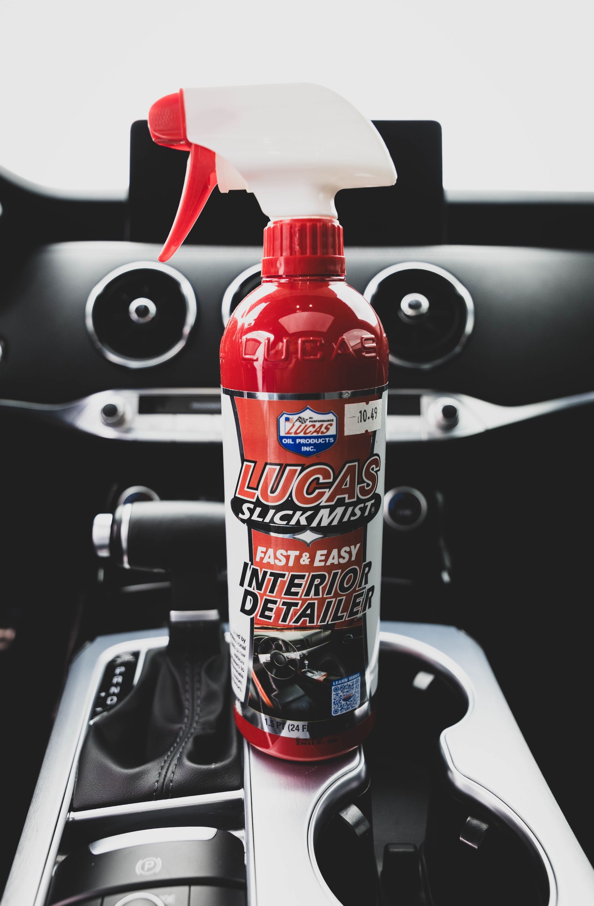 Red Lucas Slick Mist interior detailer spray bottle in a car's center console. | Mountain Top Service Center