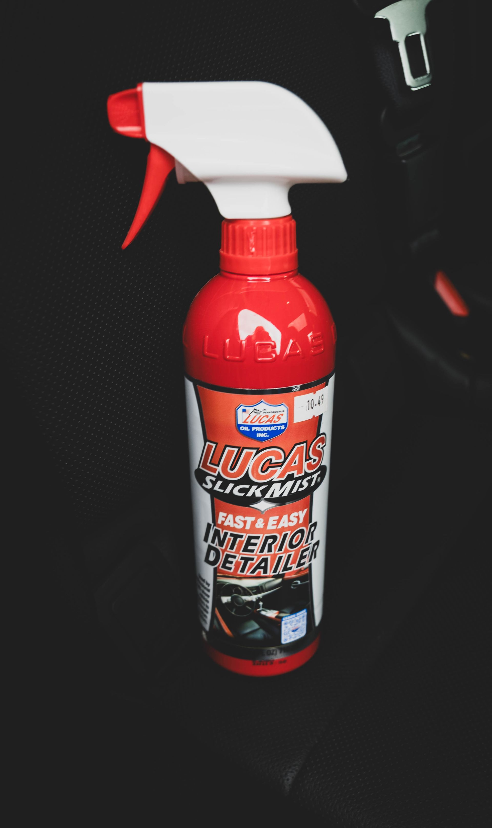 Red Lucas Slick Mist Interior Detailer spray bottle on a black car seat. | Mountain Top Service Center