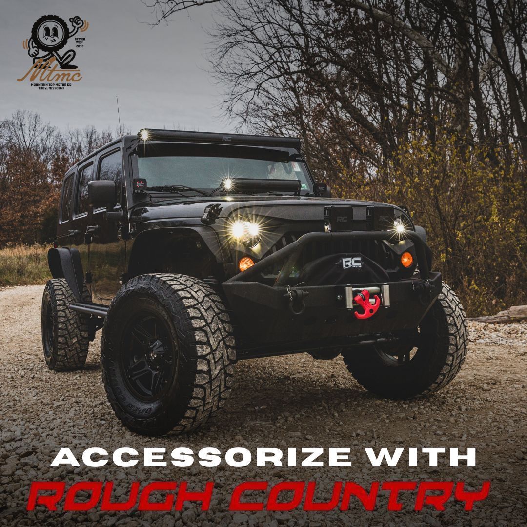 Black Jeep with off-road tires, a winch, and lights, advertising Rough Country accessories. | Mountain Top Service Center