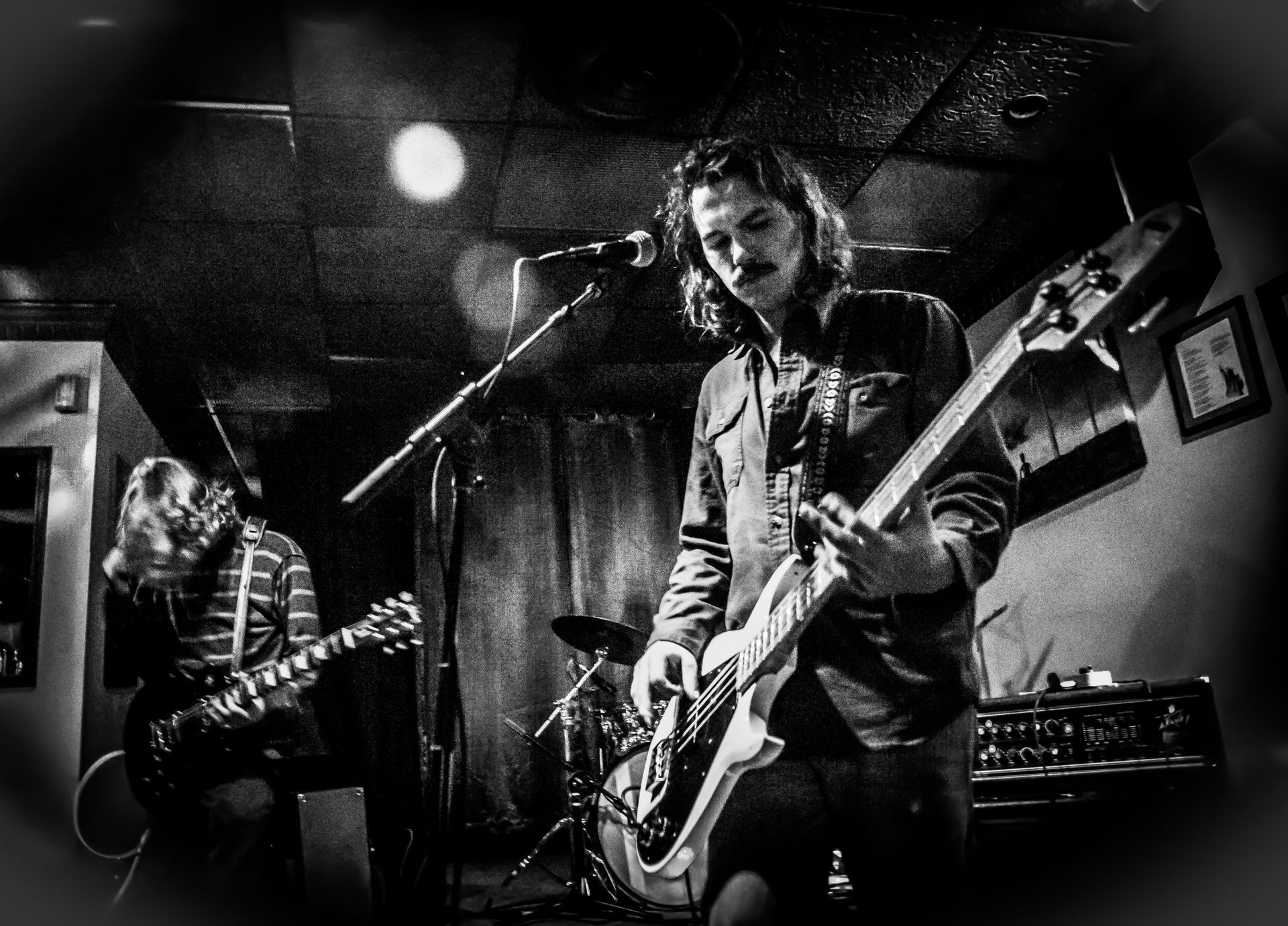 Black and white photo of a band performing on stage at a dimly lit venue.