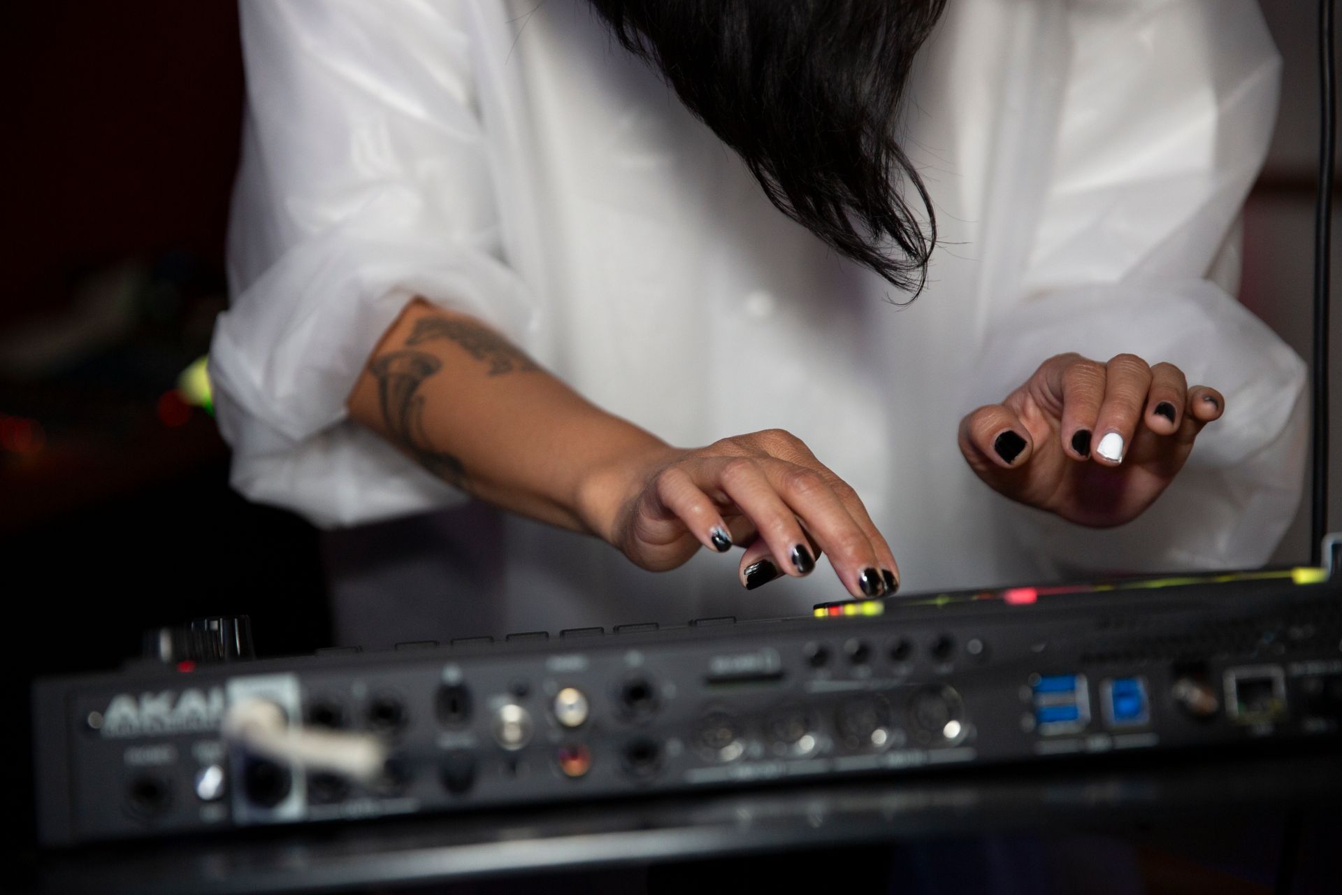 Person with dark nails playing a music synthesizer, possibly an Akai.