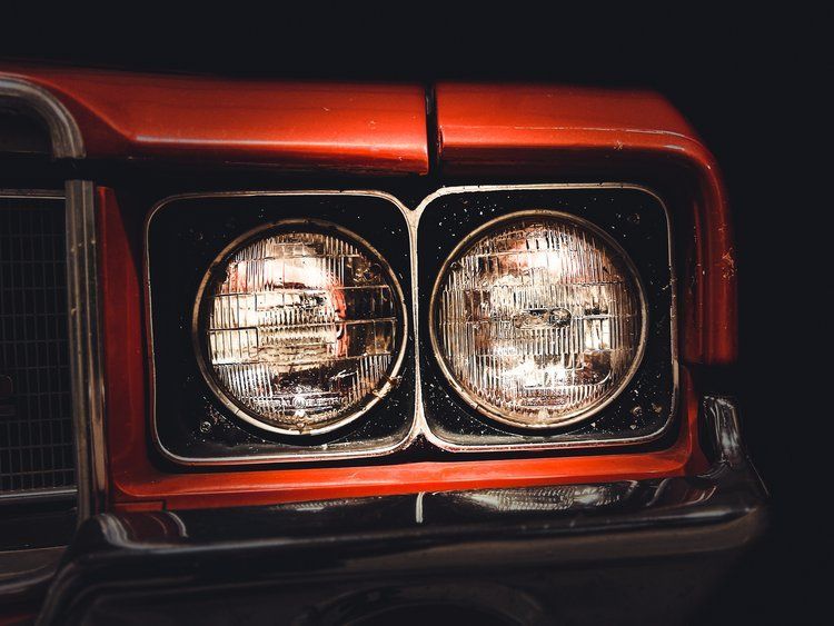 Red car headlights, close-up. Chrome trim. Black background.