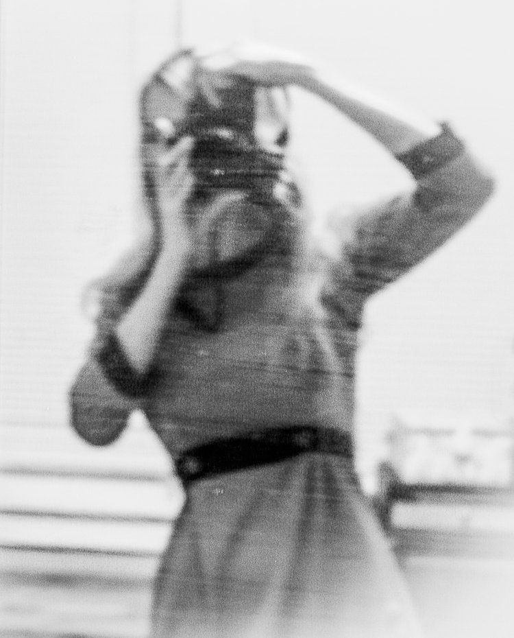 Woman with long hair taking a photo with an old camera, blurred, black and white.