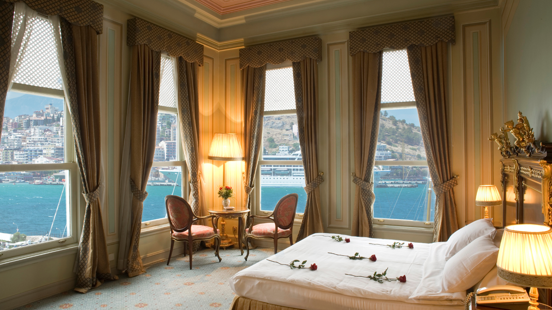 A bedroom with a bed , chairs , lamps and a view of the ocean.