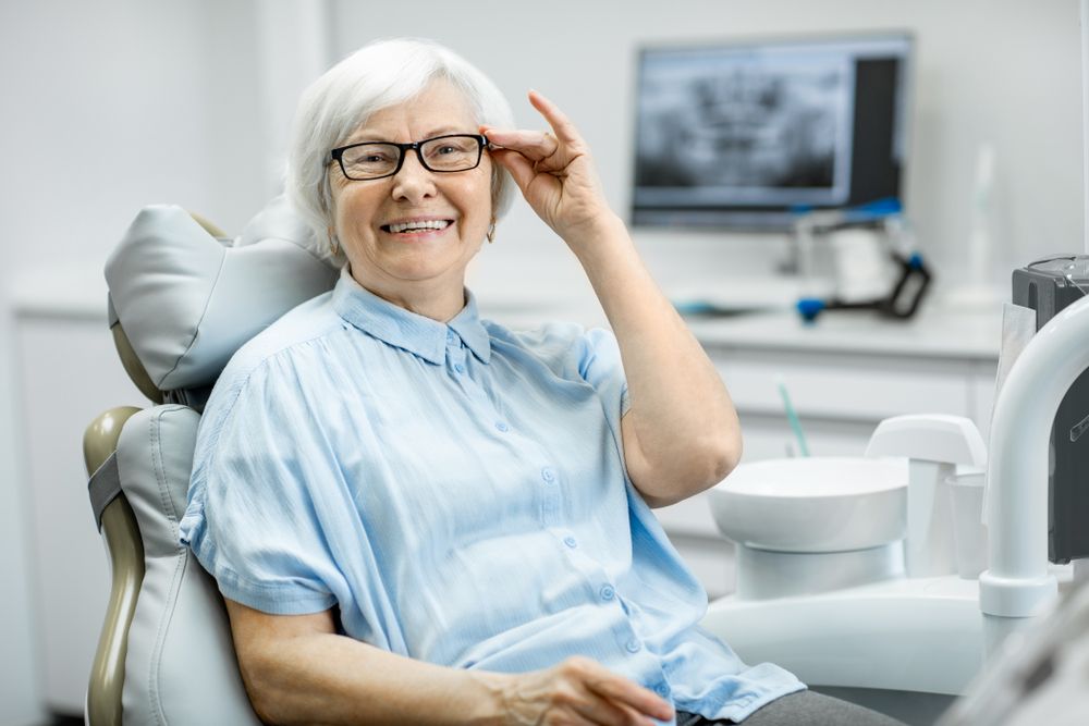 An Elderly Woman is Sitting in a Dental Chair — Bromley's Denture Clinic in Gold Coast, NSW