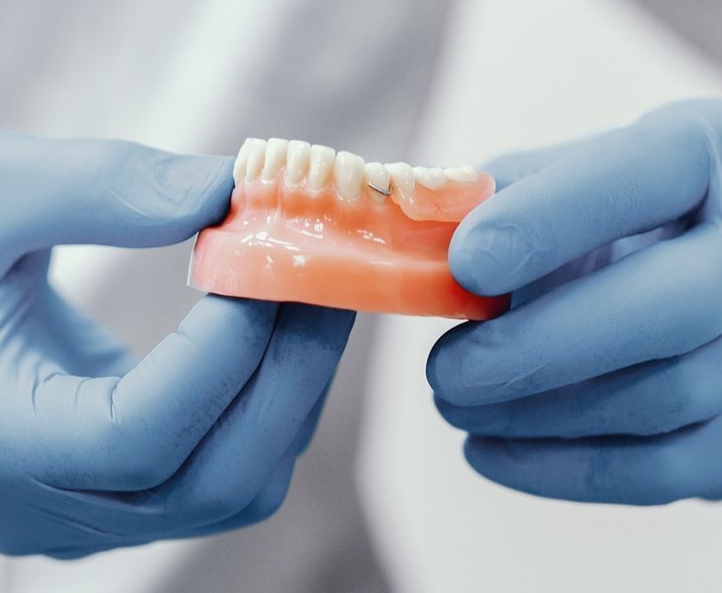 A Person Is Working on A Denture with A Tool — Bromley's Denture Clinic in Tweed Heads South, NSW