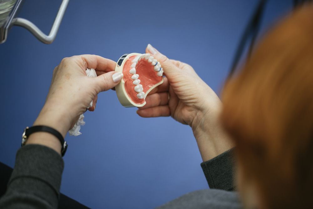 A Woman is Holding a Model of Her Teeth in Her Hands — Bromley's Denture Clinic in Tweed Heads, NSW