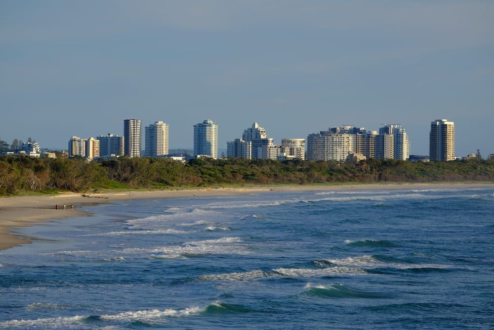 A Beach with A City Skyline in The Background and An Ocean — Bromley's Denture Clinic in Tweed Heads, NSW
