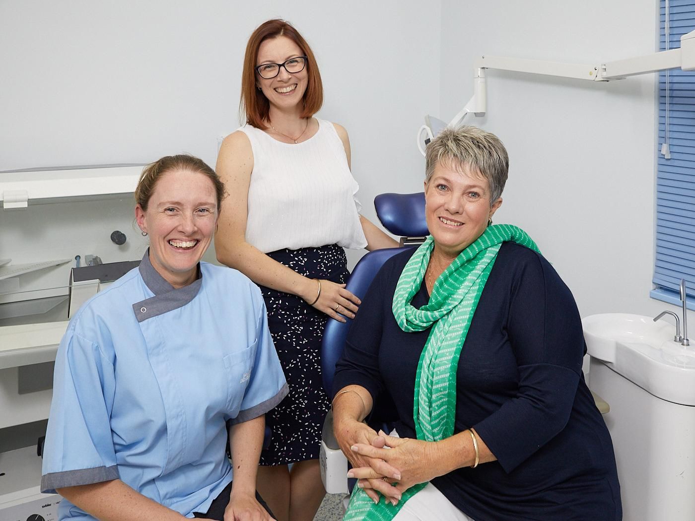 Three Women Are Posing for a Picture in a Dental Office —Bromley's Denture Clinic in Tweed Heads South, NSW