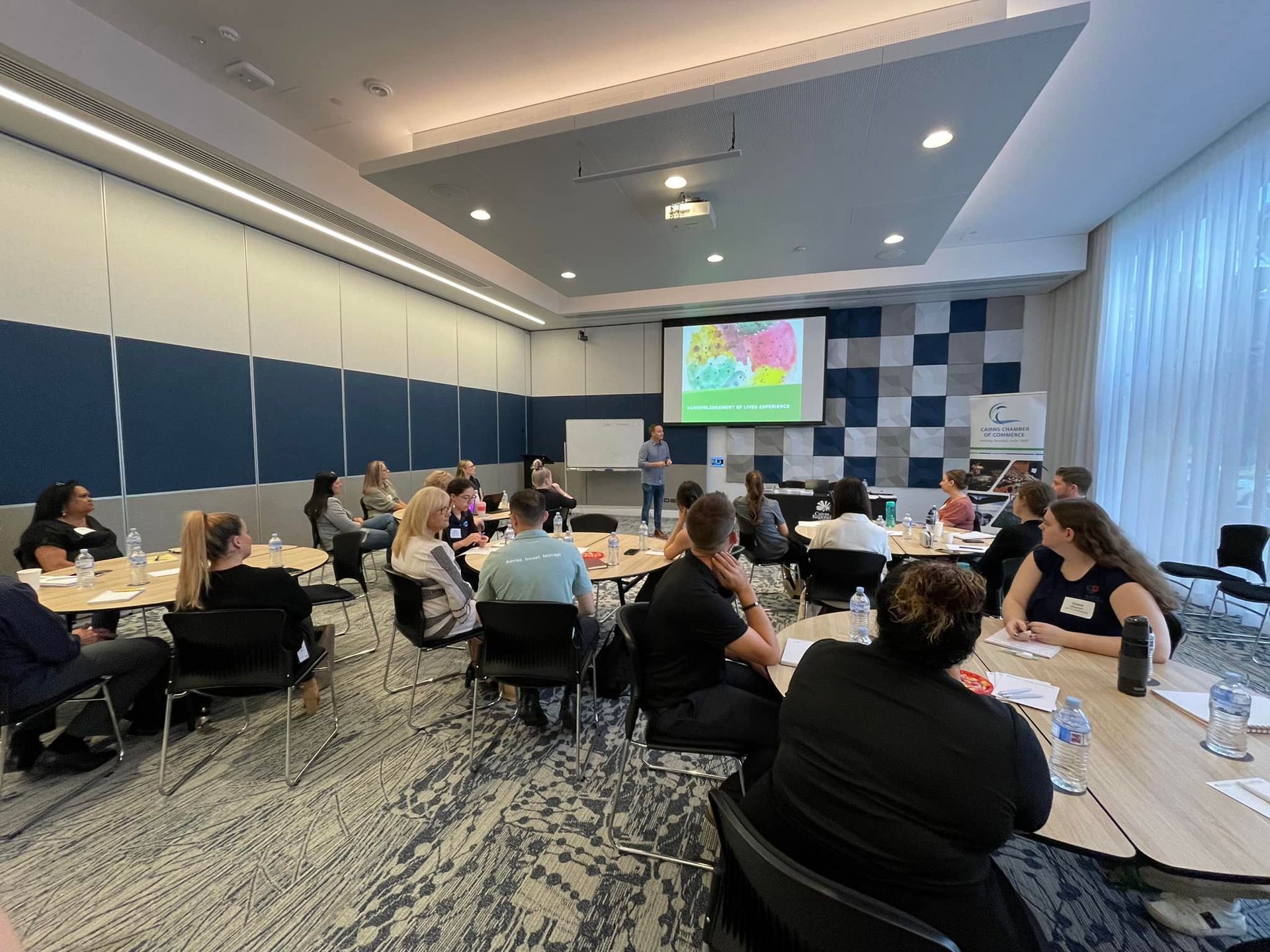 People in a meeting room, listening to a presentation on a screen. People in a meeting room, listening to a presentation on a screen.