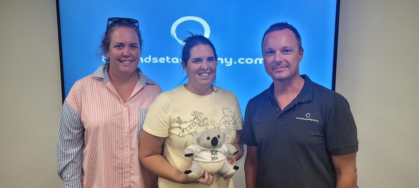 Three people standing in front of a blue screen. A woman holds a stuffed koala, everyone is smiling. Three people standing in front of a blue screen. A woman holds a stuffed koala, everyone is smiling.