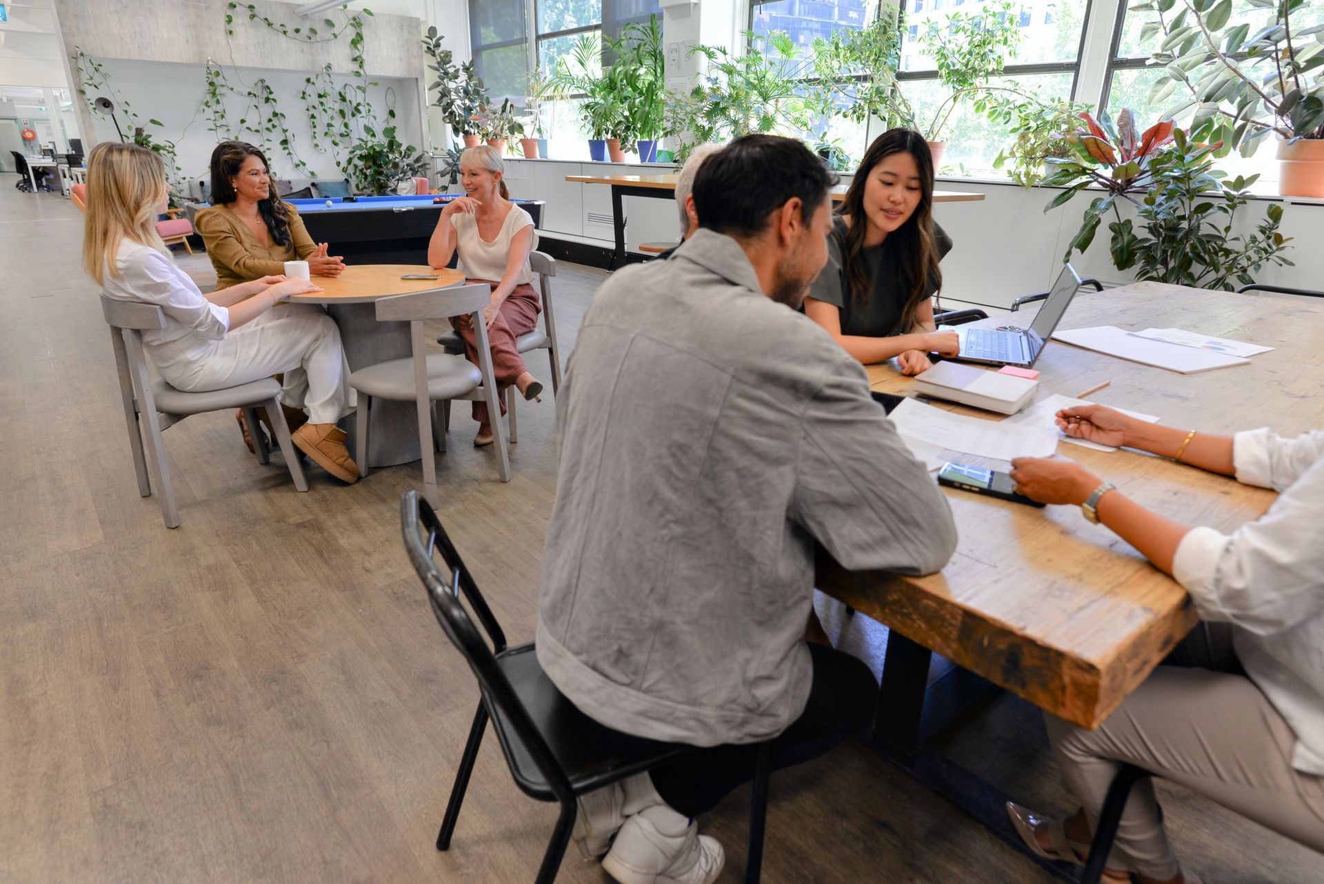 People sitting in a circle, holding hands. Inside a room.