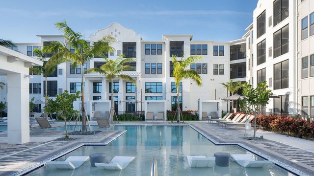 A large swimming pool in front of a large apartment building.