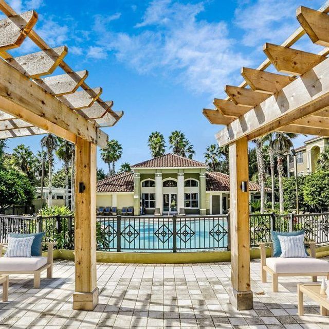 A pergola overlooking a swimming pool with a house in the background