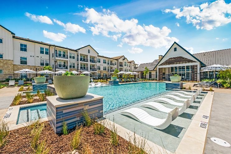 A large swimming pool in front of a large apartment building.