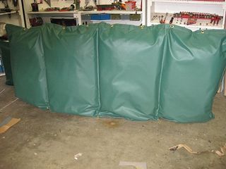 three green bags are sitting on the floor in a garage .