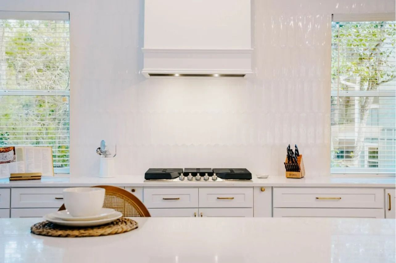 A kitchen with white cabinets and a stove top oven.
