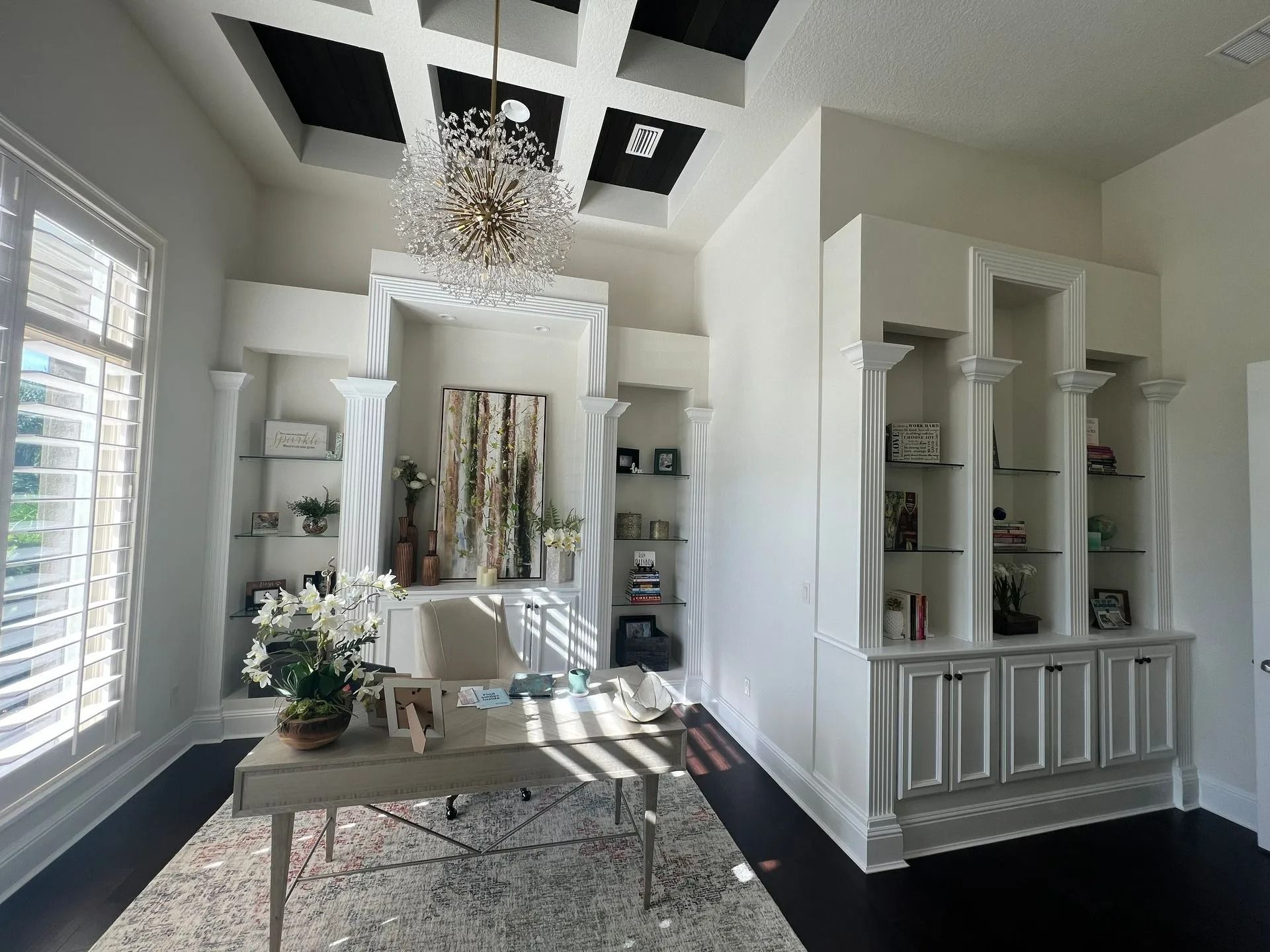 A home office with a desk and a chandelier hanging from the ceiling