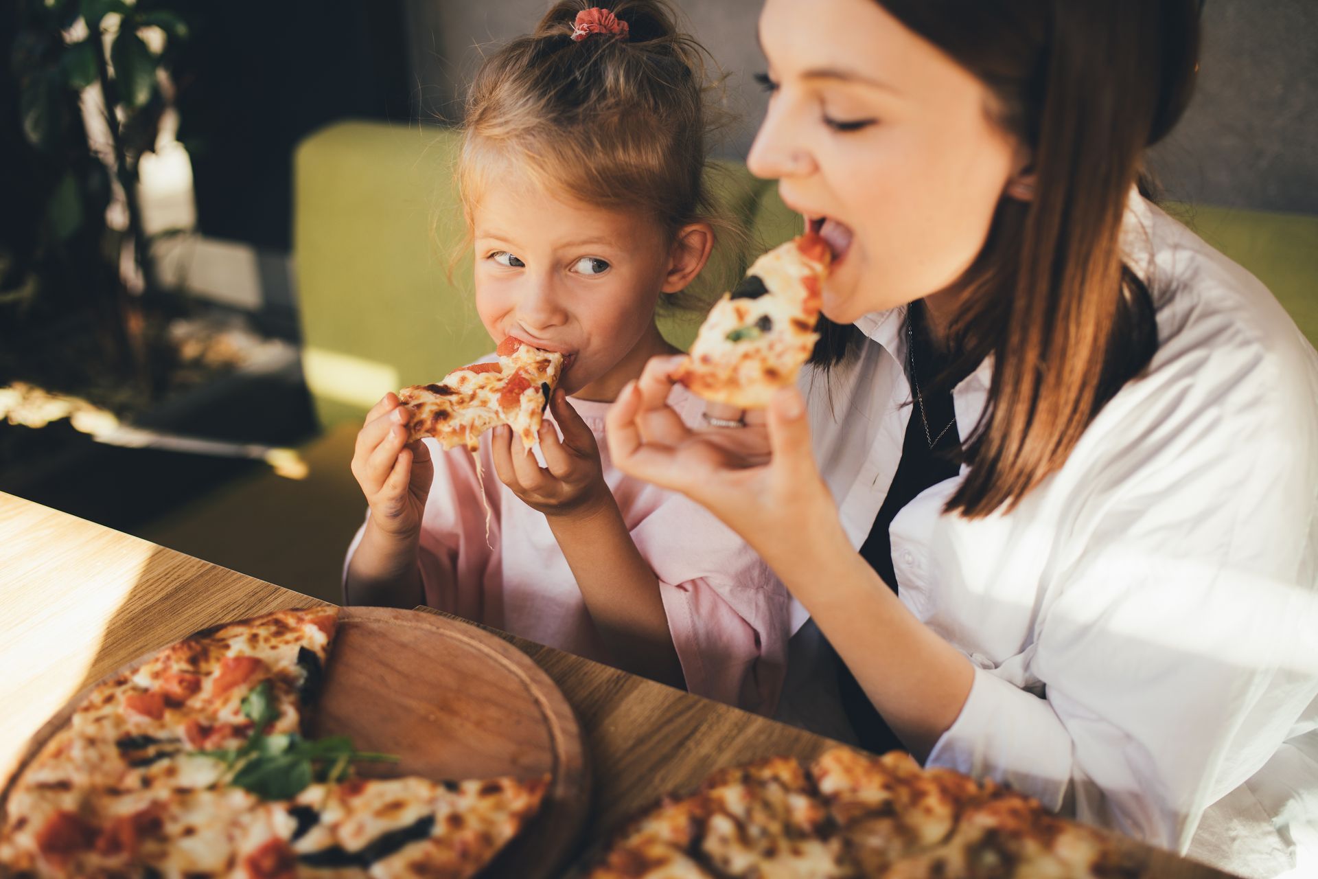 Woman and young girl enjoying pizza at a table