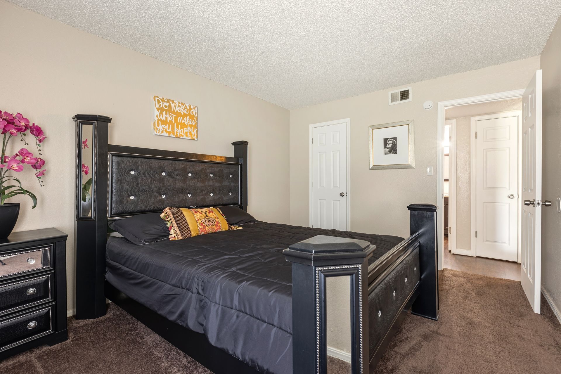 Queen size bed in bedroom with closet door. Tan room with white trim.