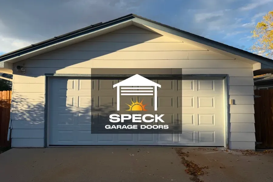 A white garage with a Speck Garage Doors logo overlaid in the center.