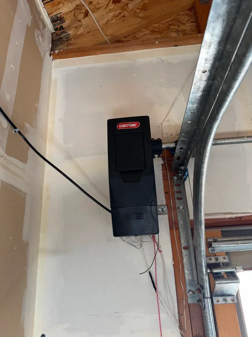 A black LiftMaster wall-mount garage door opener is installed on a white wall next to metal door tracks.