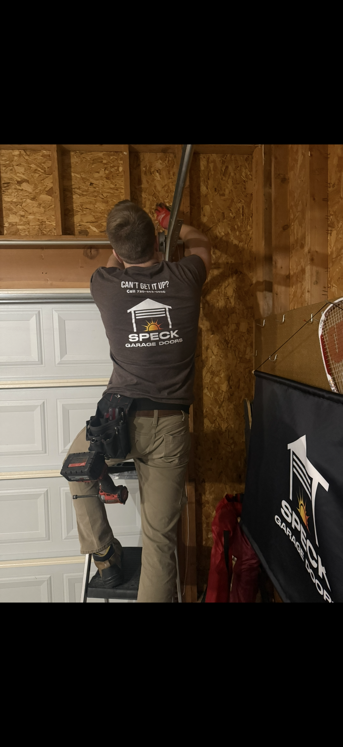 An interior view of a commercial garage featuring a large white overhead door with windows, flanked by two ladders.