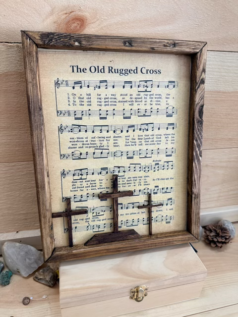 A wooden piece made by Rough Cut Wood that has The Old Rugged Cross on it.
