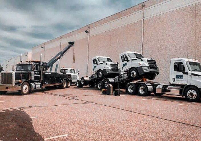 Tow trucks loading white trucks on a loading dock.