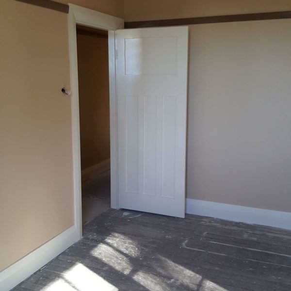 An empty room with a white door and tan walls — Axis Painting in Coffs Harbour, NSW