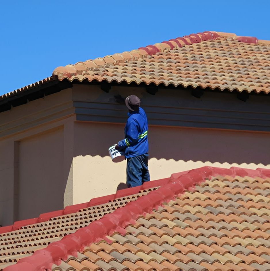 A Man Standing on Top of a Tiled Roof Holding a Bucket of Paint — Axis Painting in Coffs Harbour, NSW