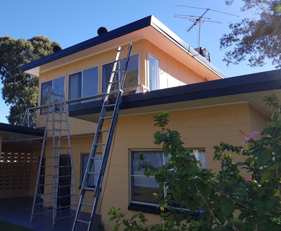A yellow house with a ladder on top of it — Axis Painting in Coffs Harbour, NSW